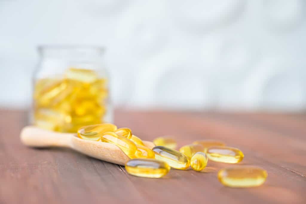Pile of Omega 3 capsules in glass bottle on wood table